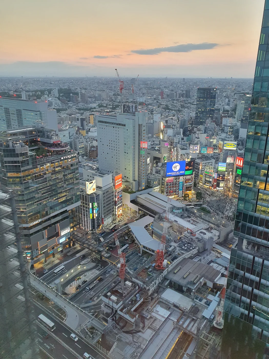 People crossing Shibuya Crossing under illuminated billboards at night